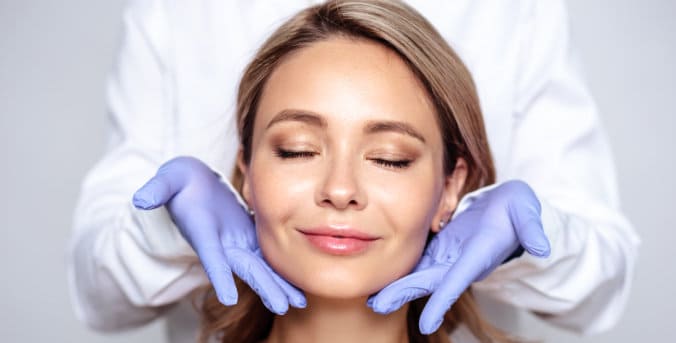 woman smiling while receiving skin treatment